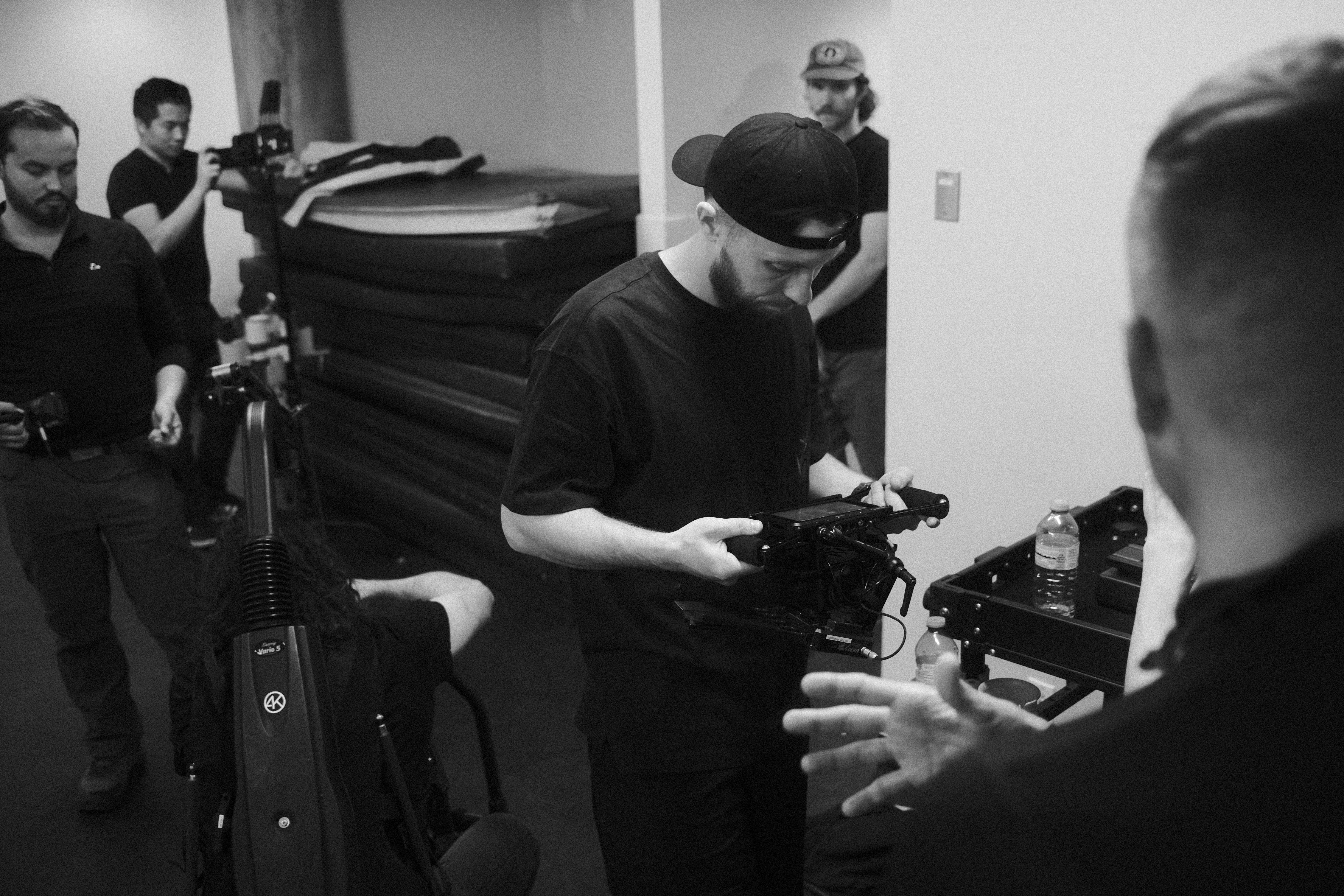 Silhouette of a camera operator filming on a professional set, surrounded by bright studio lights. The scene conveys focus and creative energy.
